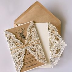 two wedding cards with lace on them are sitting next to an envelope that has a deer in it