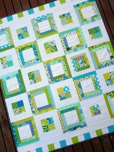 a green and white quilt sitting on top of a wooden floor