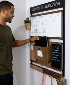 a man standing in front of a bulletin board with sticky notes and plants on it