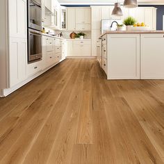 an image of a kitchen setting with wood flooring and white cabinets on the walls