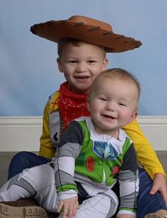 two young boys sitting on the floor wearing costumes