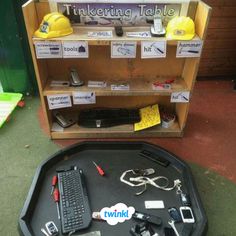 a table topped with lots of assorted items on top of a black tray next to a wooden shelf