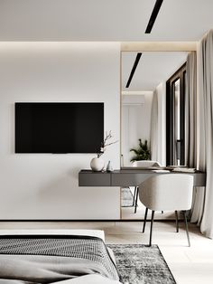 a bedroom with a bed, desk and television mounted to the wall in front of it