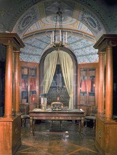 an ornate room with columns, curtains and a table in front of the door that leads to another room