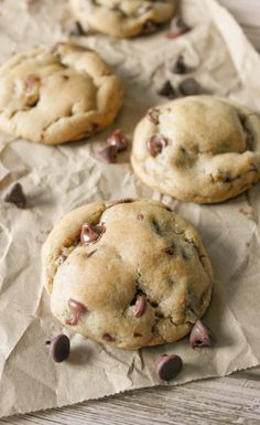 three chocolate chip cookies sitting on top of a piece of wax paper