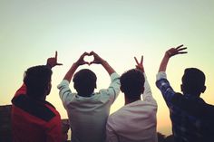 three men are standing with their hands in the shape of a heart and making a hand sign