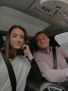 a man and woman sitting in the back seat of a car smiling at the camera