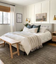 a bedroom with a bed, nightstands and pictures hanging on the wall above it