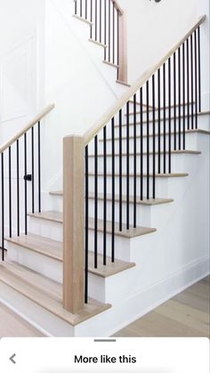 a staircase with black railing and wooden handrails on the bottom, next to a white door