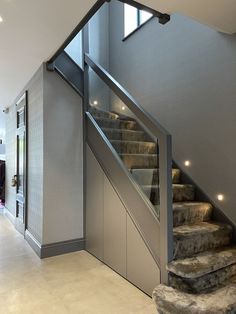 a staircase with glass railing and metal handrails in a modern style home setting