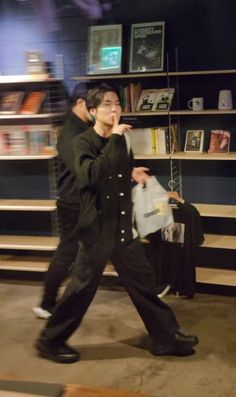 two men walking down the street in front of bookshelves