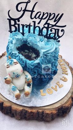 a birthday cake with blue frosting and an elephant figurine sitting on top