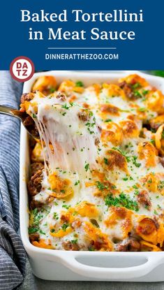 baked tortellini in meat sauce is being lifted from a casserole dish