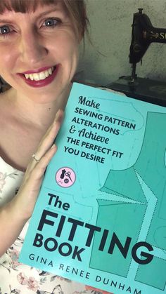 a woman holding up a book in front of her face and smiling at the camera