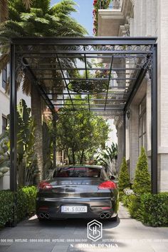 a car is parked under an awning in front of a building with trees and bushes