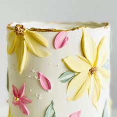 a white cake with yellow and pink flowers on it's icing, sitting on a table