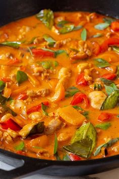 a pan filled with chicken and vegetables on top of a stove