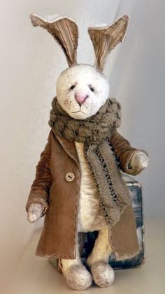 a stuffed rabbit wearing a coat and scarf