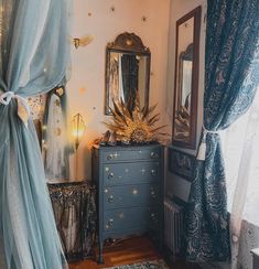 a bedroom with blue curtains and gold stars on the walls, an ornate dresser in front of a window