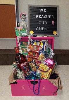 a pink trunk filled with candy and other items in front of a sign that says we treasure our chest