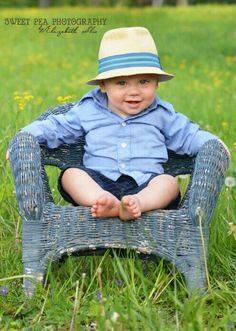 a little boy sitting on top of a blue chair in the middle of a field