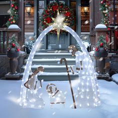 a lighted arch in front of a house with christmas decorations on the steps and wreaths