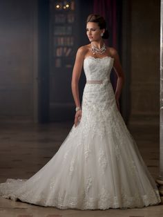 a woman in a wedding dress standing next to a pillar with her hands on her hips