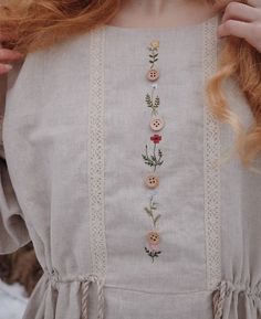 a close up of a person wearing a dress with flowers and buttons on the front