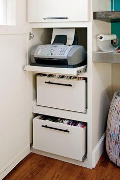 a white cabinet with two drawers and a printer on the top shelf next to it