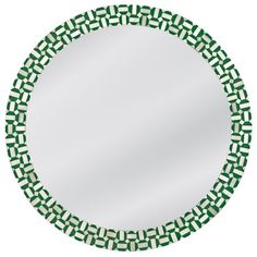 a round mirror with green and white designs on the rim, in front of a white background