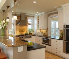 a large kitchen with white cabinets and granite counter tops, along with wooden stairs leading up to the second floor