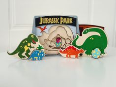 three wooden dinosaurs are standing in front of a sign that says jurassi park