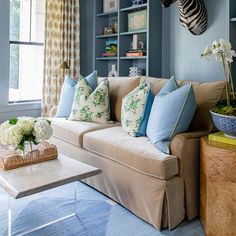 a living room filled with furniture and a zebra head mounted on the wall above it