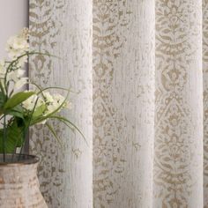 a vase with white flowers sitting next to a curtain in front of a window sill