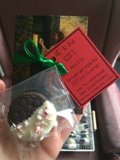 a hand holding an oreo cookie with white chocolate and sprinkles