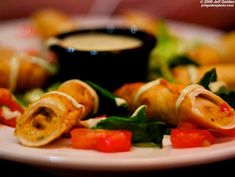 a white plate topped with vegetable rolls and dipping sauce