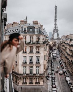 the eiffel tower in paris is seen from an apartment window with cars parked on the street below