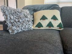 a couch with two pillows on it and a pillow that has pine trees on it