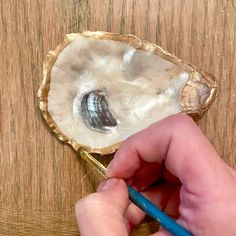 a person holding a pencil in front of a piece of food on a wooden table