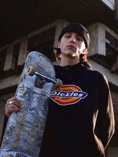 a man holding a skateboard in front of a building