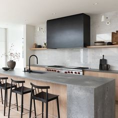 a modern kitchen with an island counter and bar stools next to the stove top