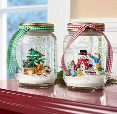 two glass jars filled with snow and christmas decorations