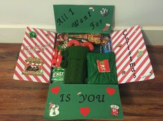 an open christmas gift box with items inside it on a wooden floor in front of a wall