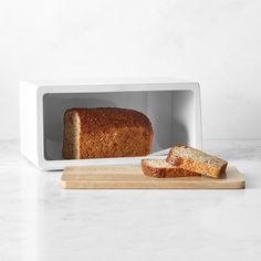 a loaf of bread sitting in a microwave on a cutting board next to a slice of bread