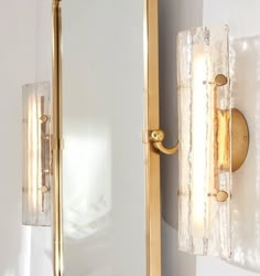 two lights on the wall next to each other in front of a mirror and light fixture