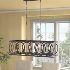 a chandelier hanging over a dining room table with chairs and a potted plant