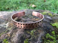 a metal bracelet sitting on top of a rock