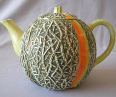 a ceramic teapot with an orange stripe on the bottom and green trim around it