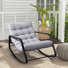 a rocking chair sitting on top of a rug next to a potted plant