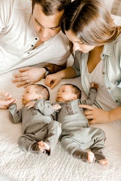 a man and woman laying on top of a bed with two babys